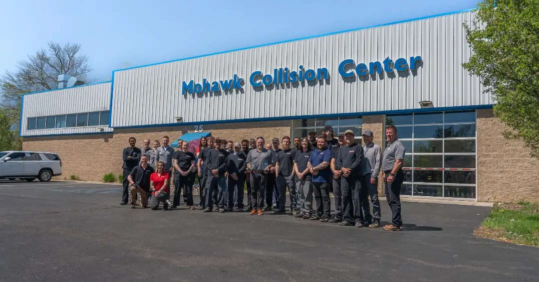 Group of men and women in front of a building that saying Mohawk Collision Center.
